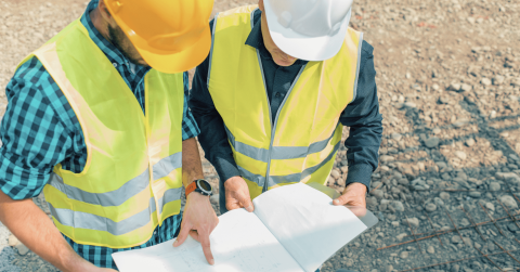 Projectmanagement, vergadering tussen twee mannen die plan gebouw vasthouden